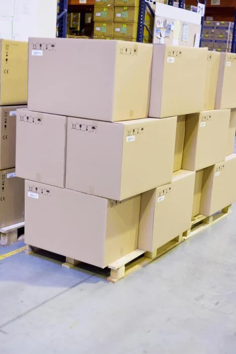 Colis en carton empilés sur palette dans un entrepôt, prêts à être expédiés